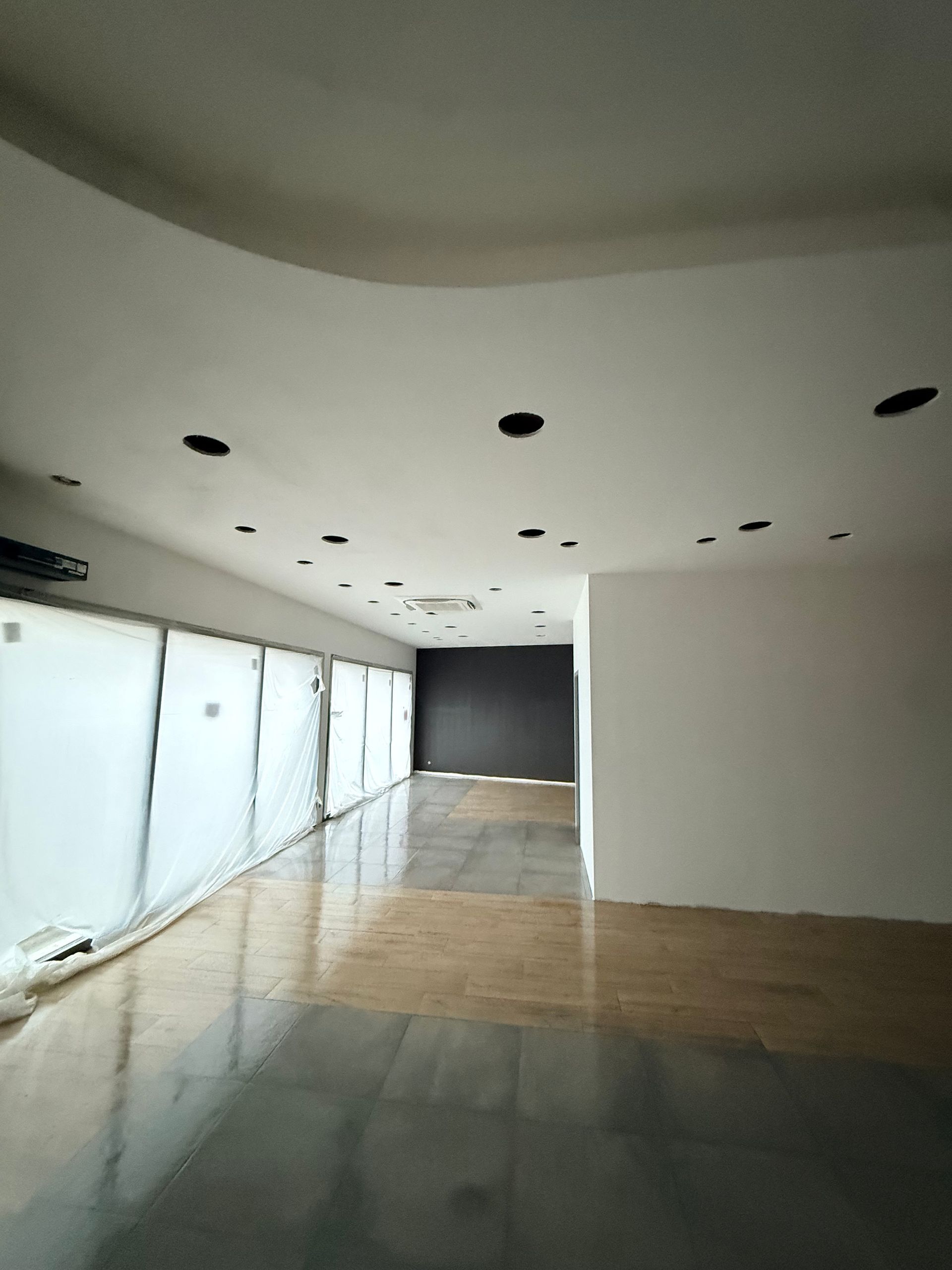 Couloir moderne vide aux murs blancs, éclairage encastré au plafond et carrelage réfléchissant au sol.