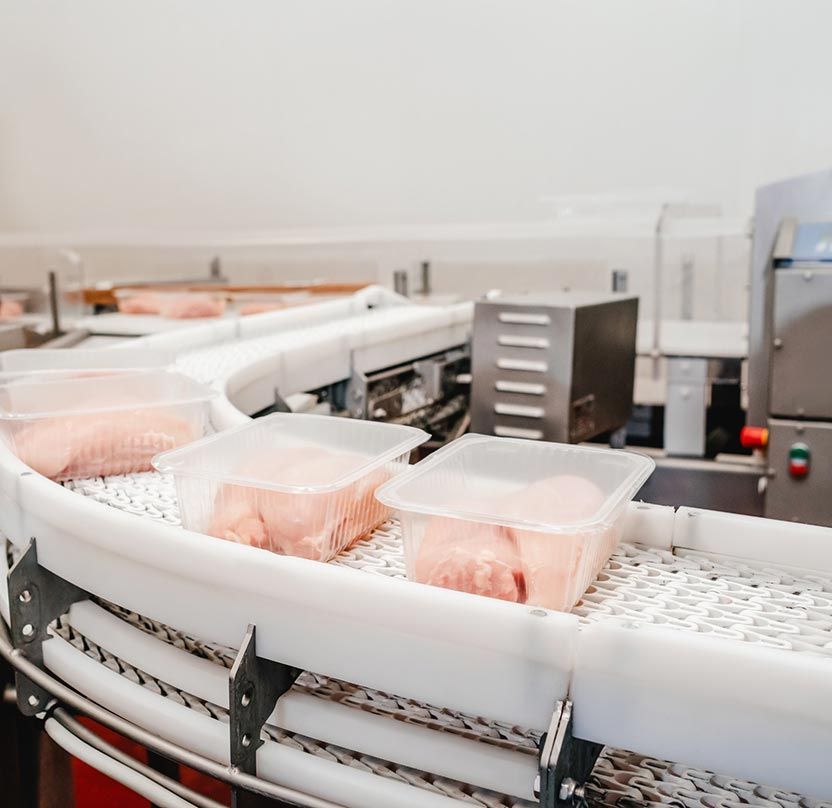 Una cinta transportadora llena de contenedores de plástico de alimentos en una fábrica.