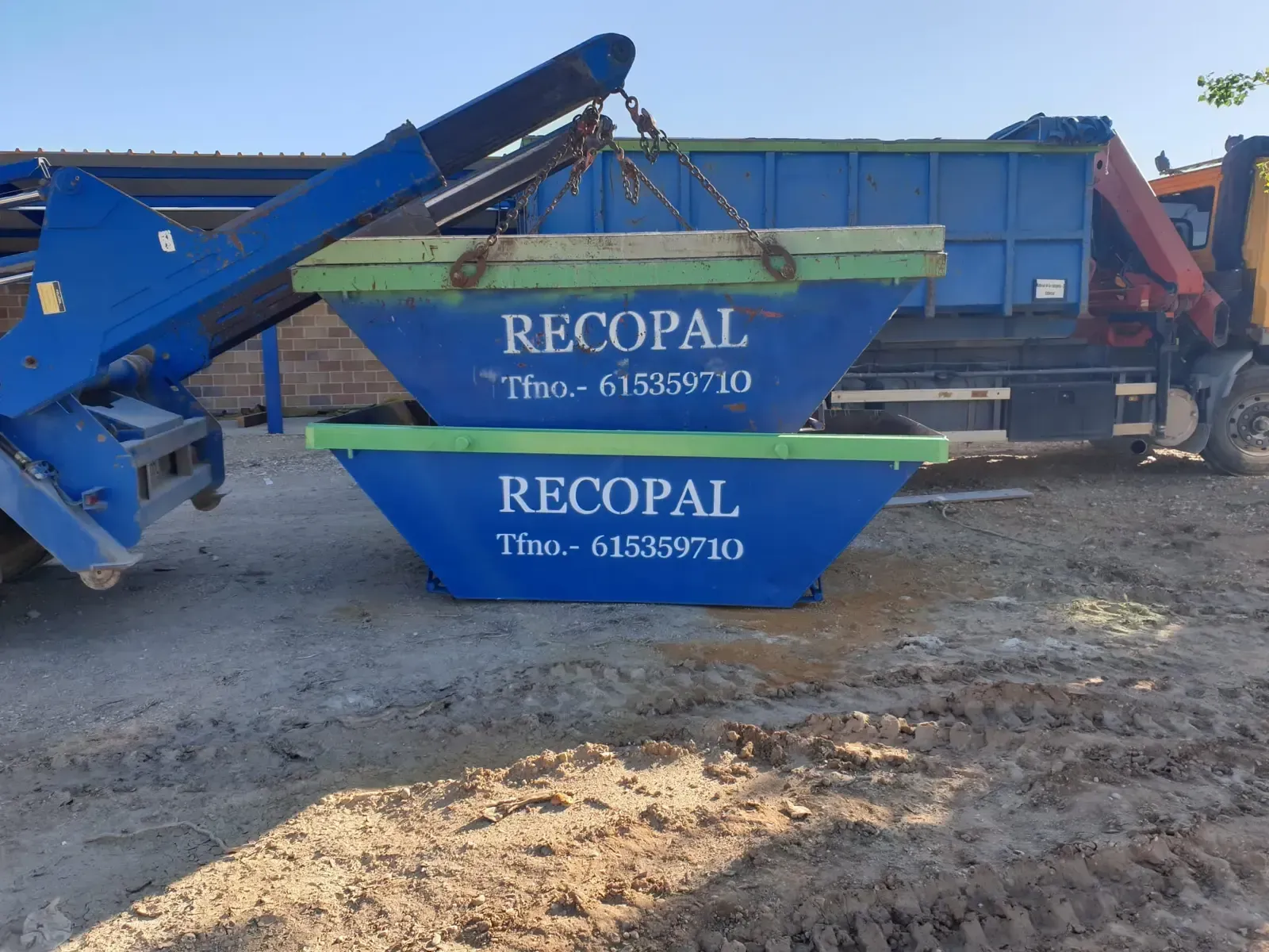 Dos excavadoras amarillas y un camión amarillo estacionados en un campo fangoso bajo un cielo nublado.