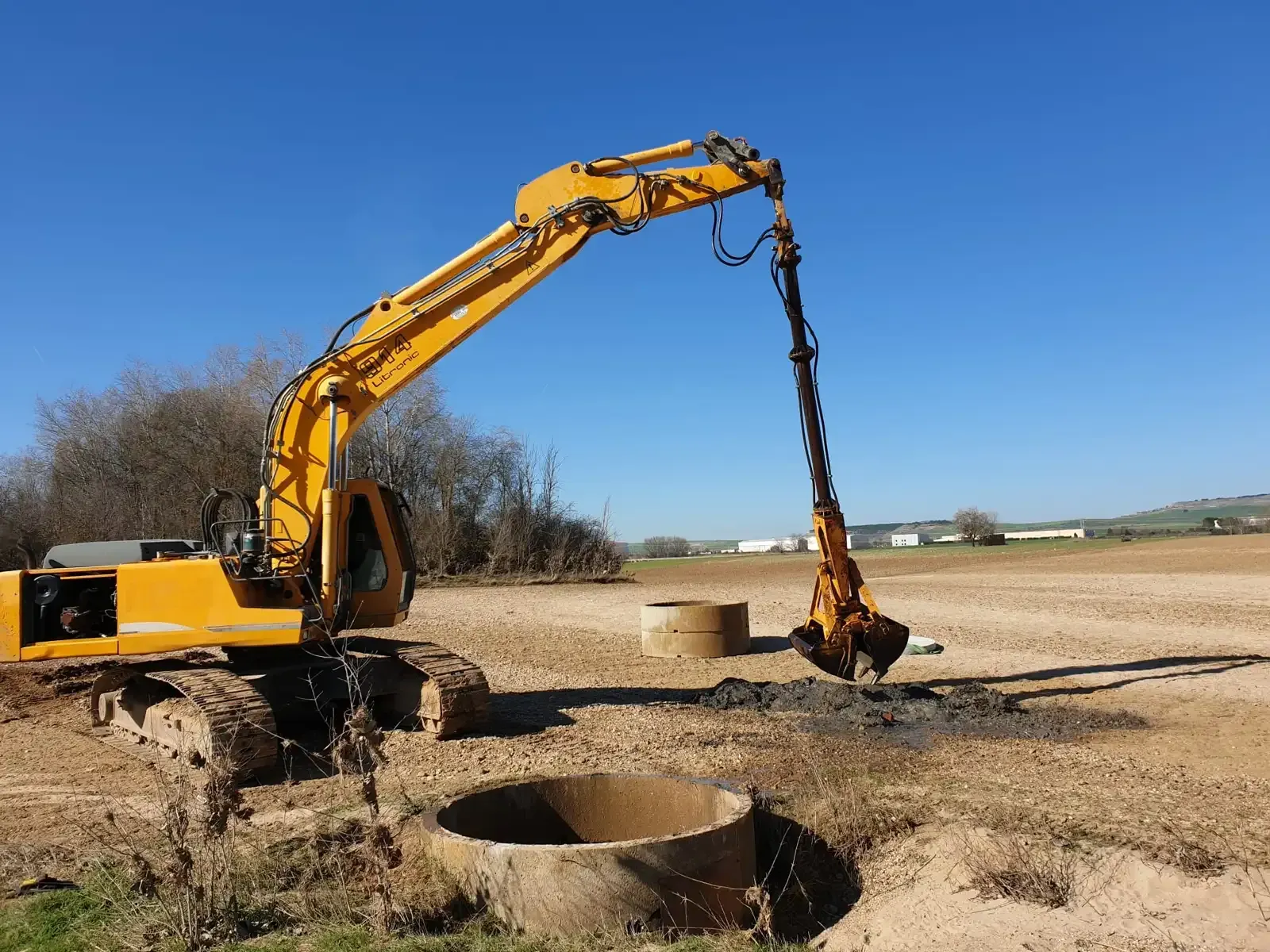 Dos camiones amarillos estacionados en un camino de tierra en un campo bajo un cielo azul con nubes.