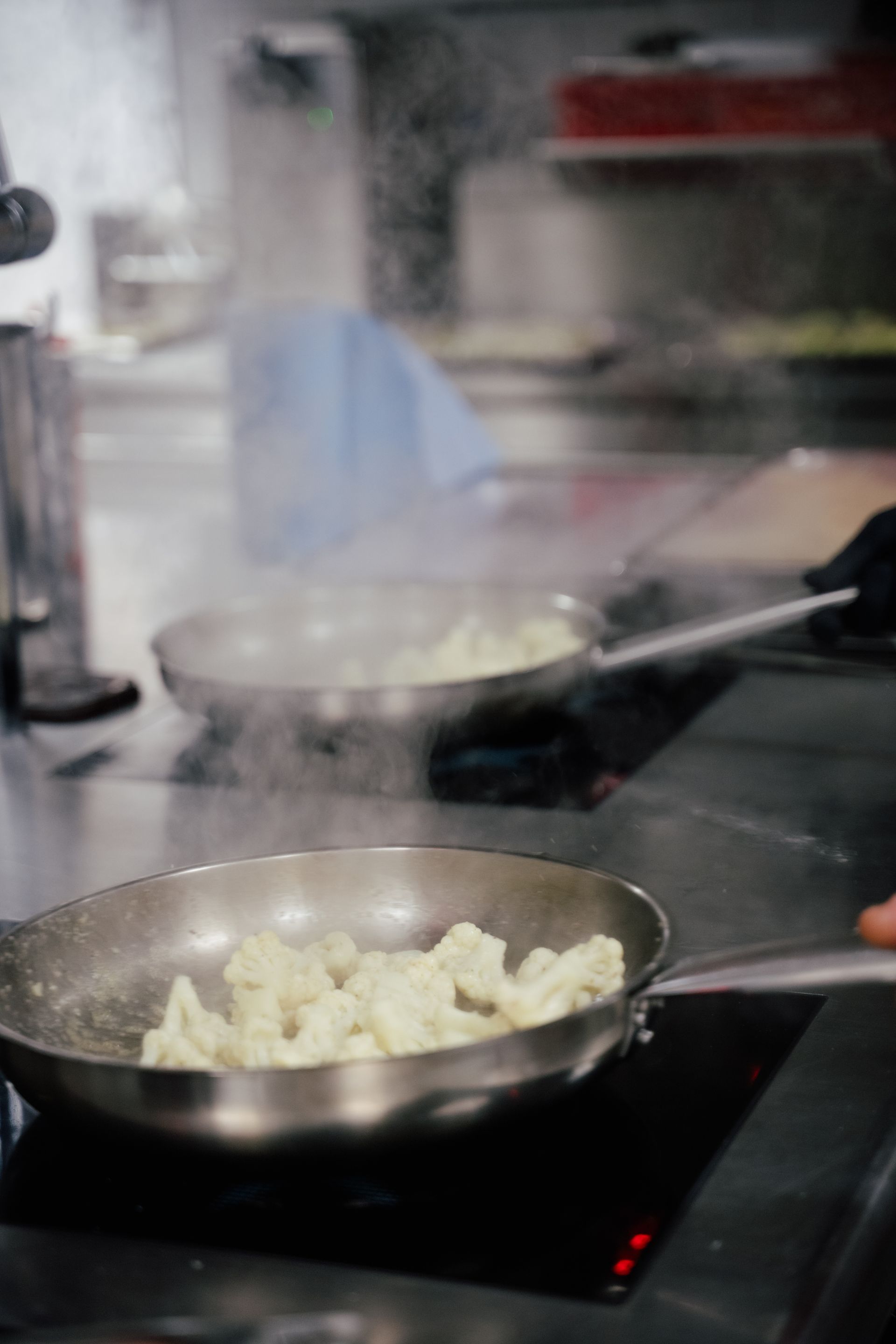 Töpfe mit Essen, die in einer dampfenden Großküche auf einem Herd kochen