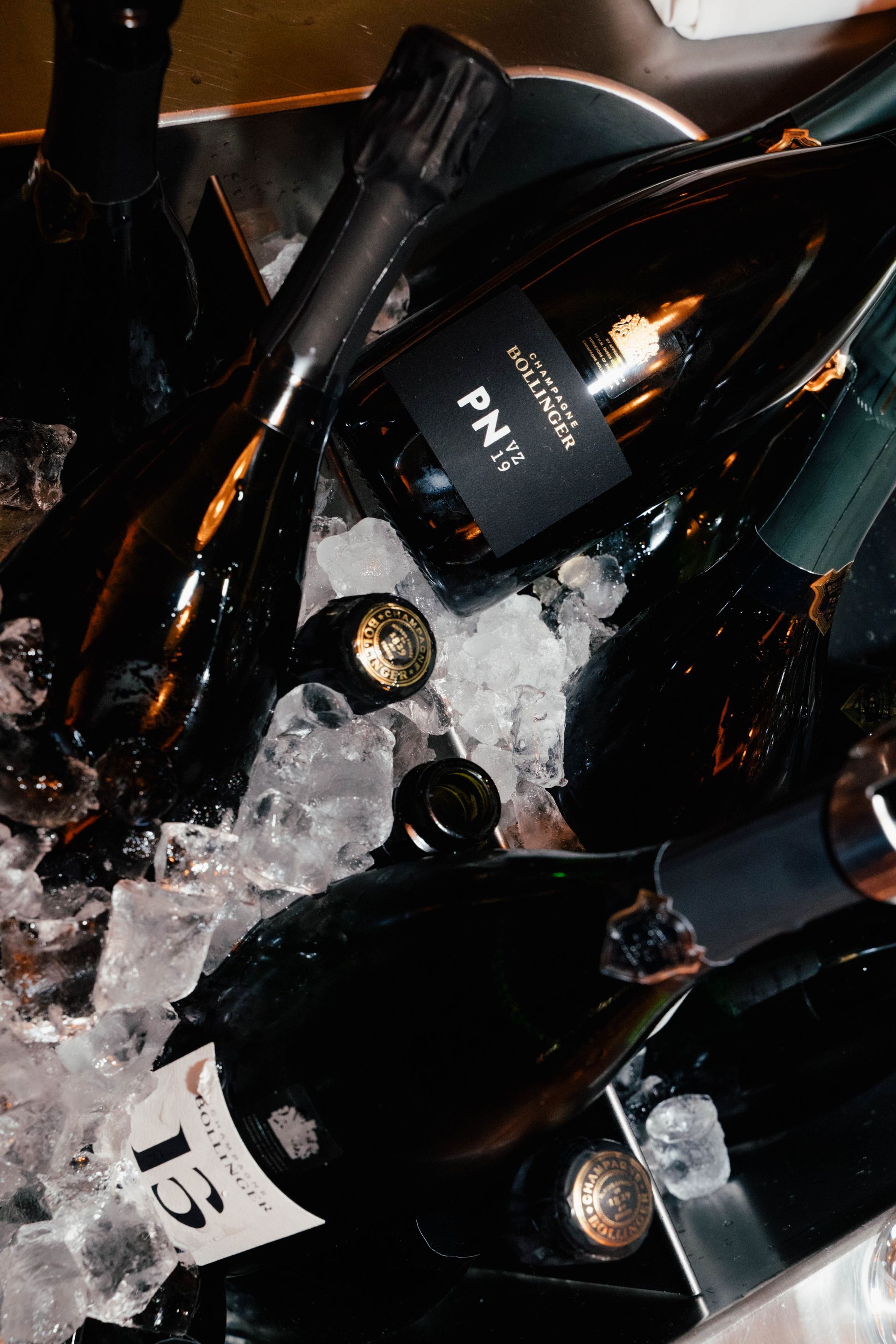 Mehrere dunkle Champagnerflaschen aus Glas, eingebettet in einen Eiskübel.