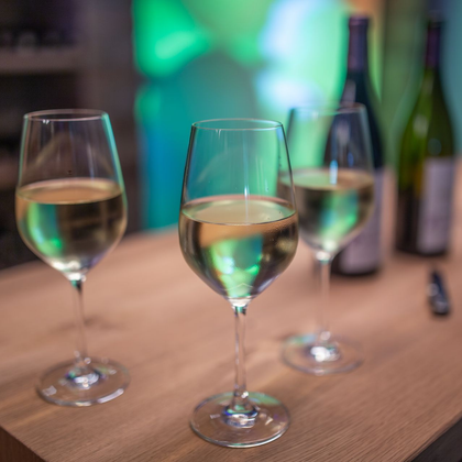 Eine Person, die eine schwarze Schürze mit der Aufschrift „DIEL“ trägt, gießt Rotwein aus einer Glasflasche in eine Karaffe aus klarem Glas.