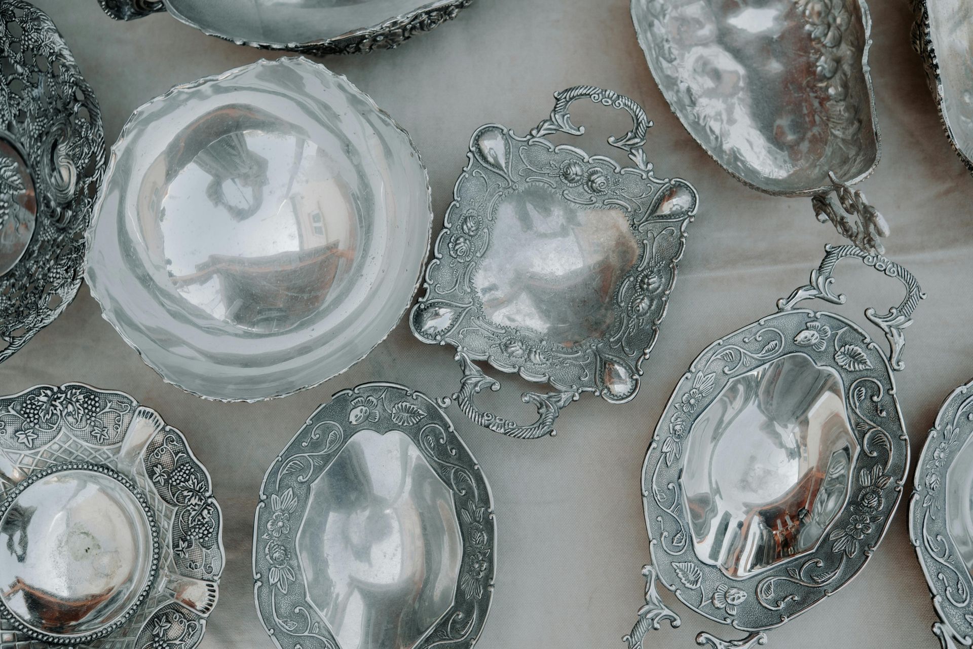 Piedras decorativas de plata con bordes ornamentados sobre un fondo pálido.