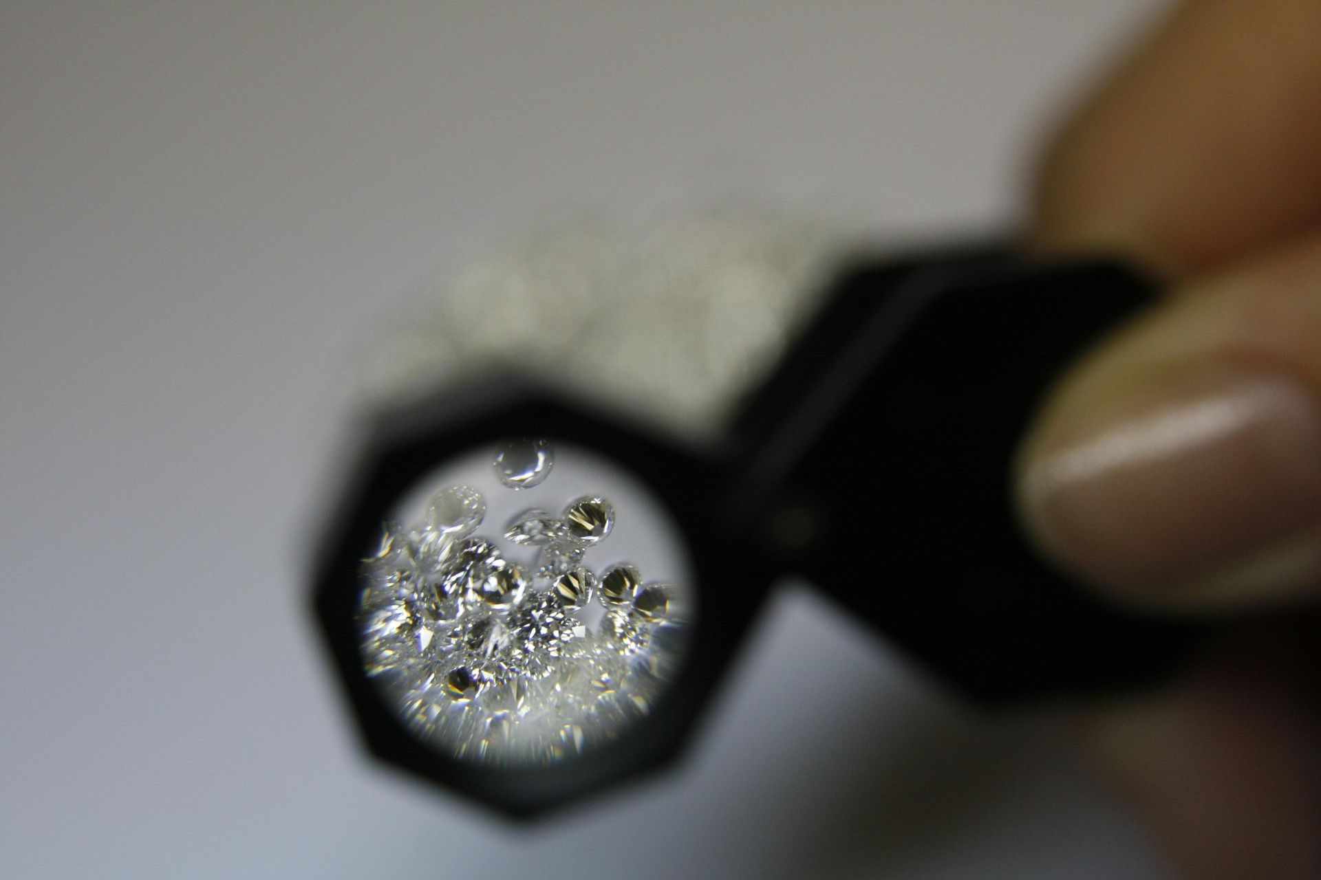 Lupa sostenida sobre pequeñas piedras brillantes sobre un fondo blanco.