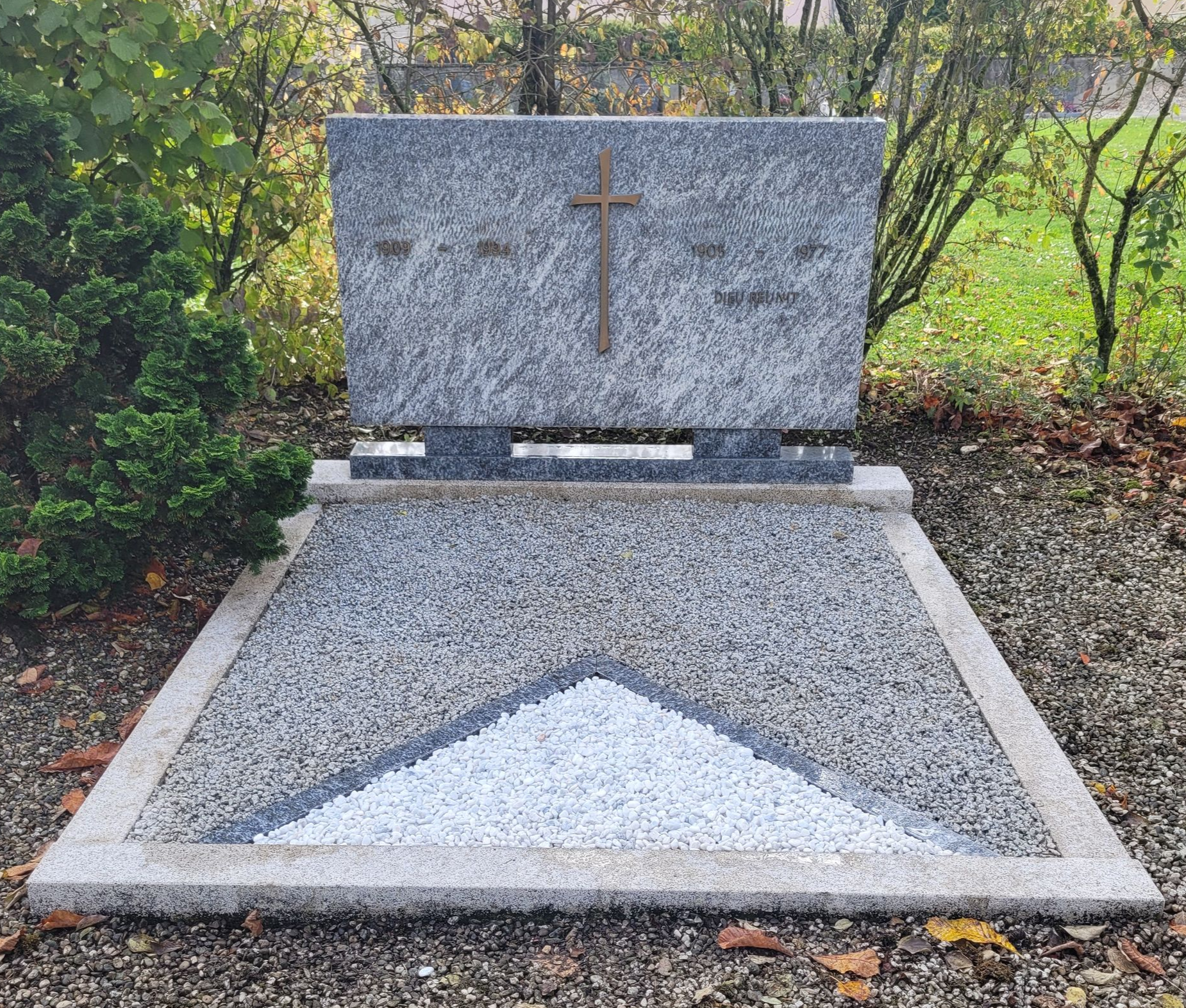 Pierre tombale en granit rouge en forme de cœur avec une découpe en forme de cœur, placée sur une parcelle de gravier 
