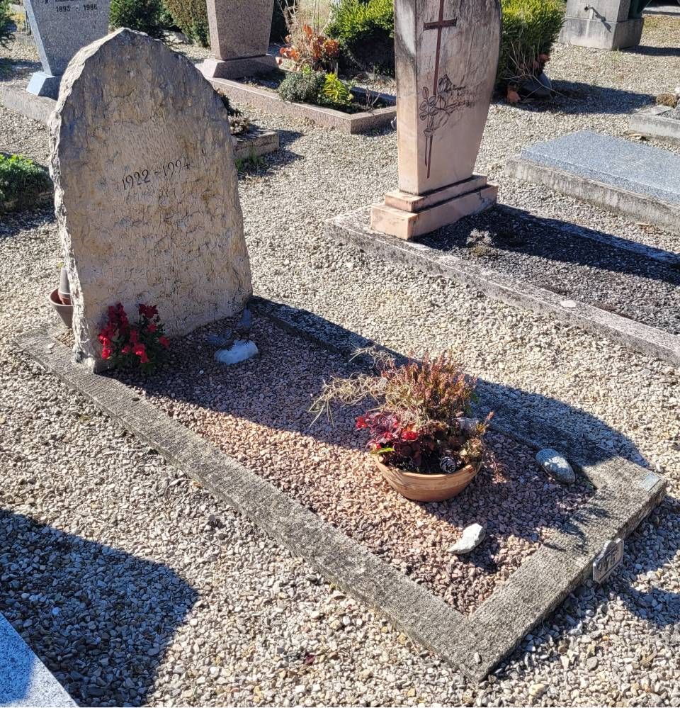 Cimetière de gravier avec deux pierres tombales et des fleurs en pot sur une sépulture
