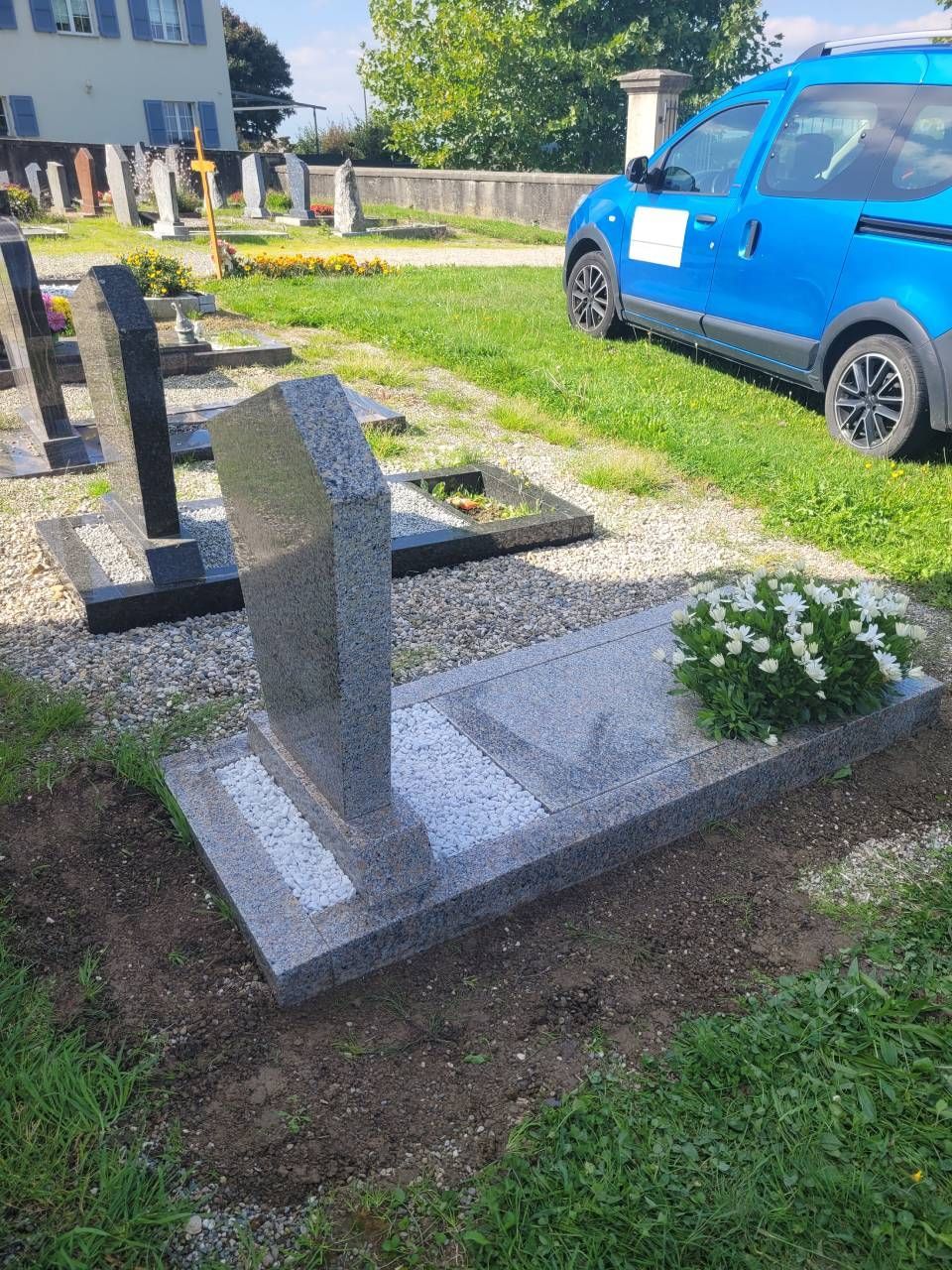 Des pierres tombales dans un cimetière, à côté d'une voiture bleue, par une journée ensoleillée.