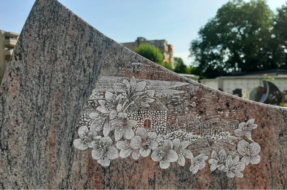 Une fresque florale peinte sur une sculpture en pierre, avec un pont et des bâtiments en arrière-plan.