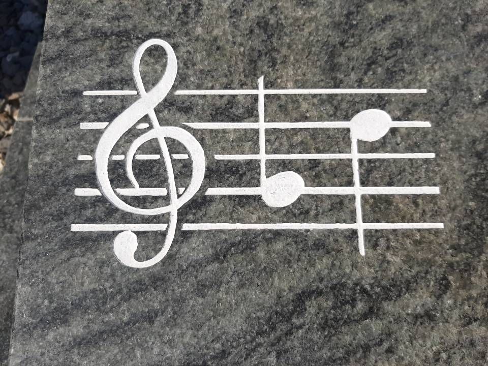 Des notes de musique blanches et une clé de sol peintes sur une surface de pierre grise
