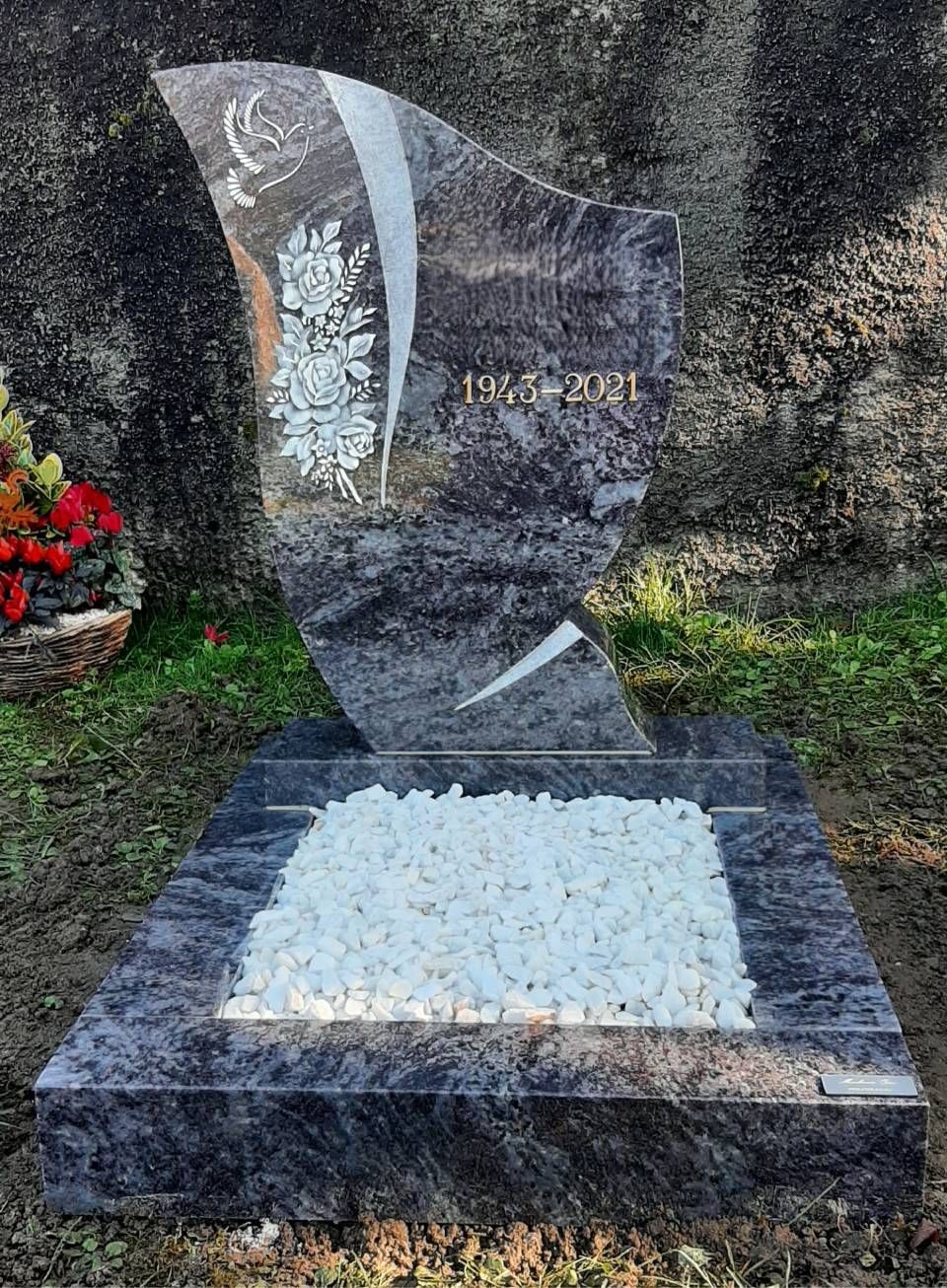 Pierre tombale commémorative moderne en granit noir avec gravure florale blanche et socle orné de fleurs blanches