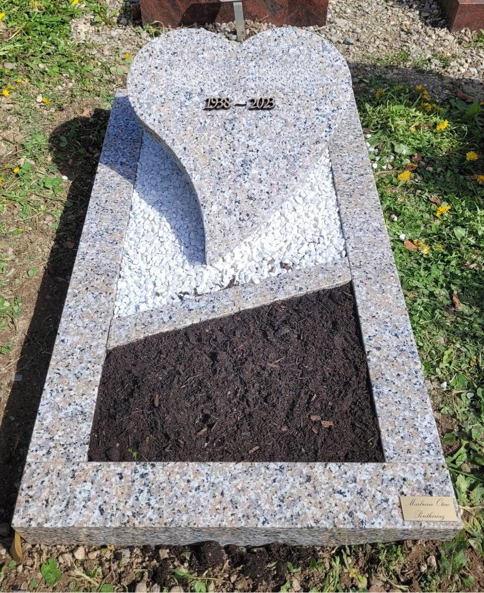 Pierre tombale en granit avec un parterre de fleurs intégré et une petite plaque dans un cimetière