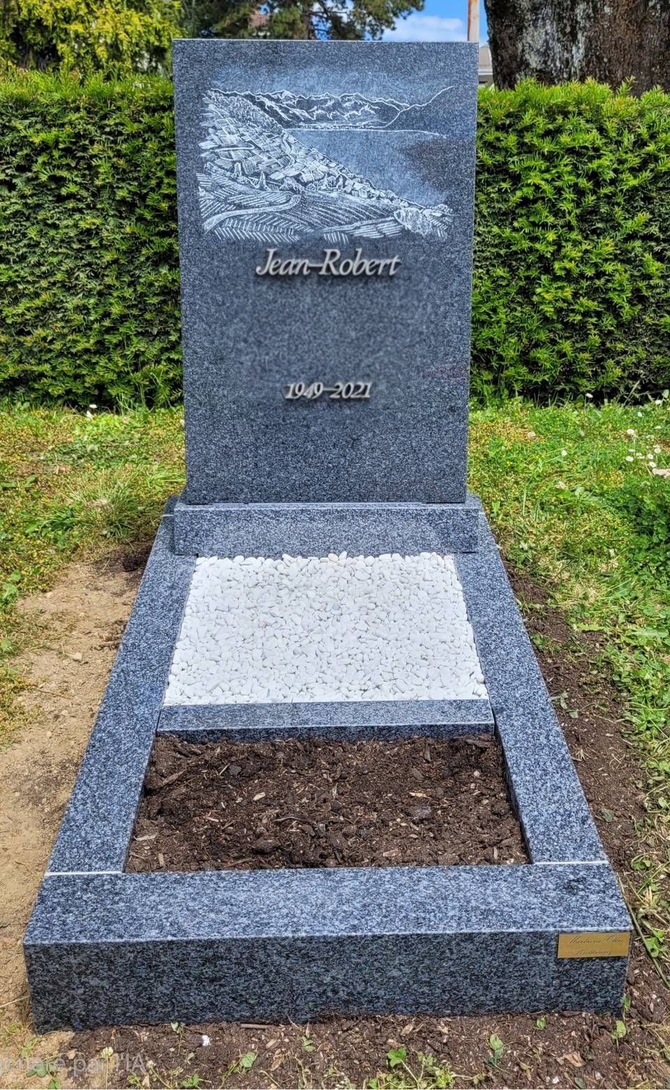 Pierre tombale en granit avec plaque gravée et emplacement de terre fraîche dans un cimetière verdoyant