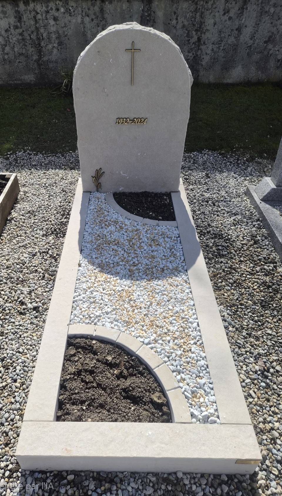 Pierre tombale blanche avec croix et mosaïque incrustée dans un cimetière