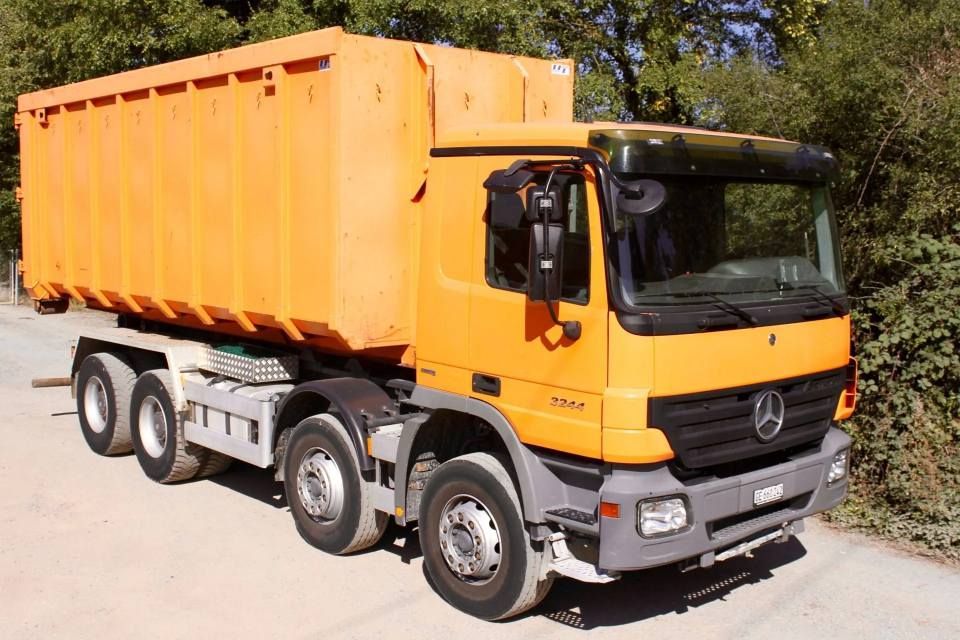 Un camion Mercedes orange est garé sur le bord de la route