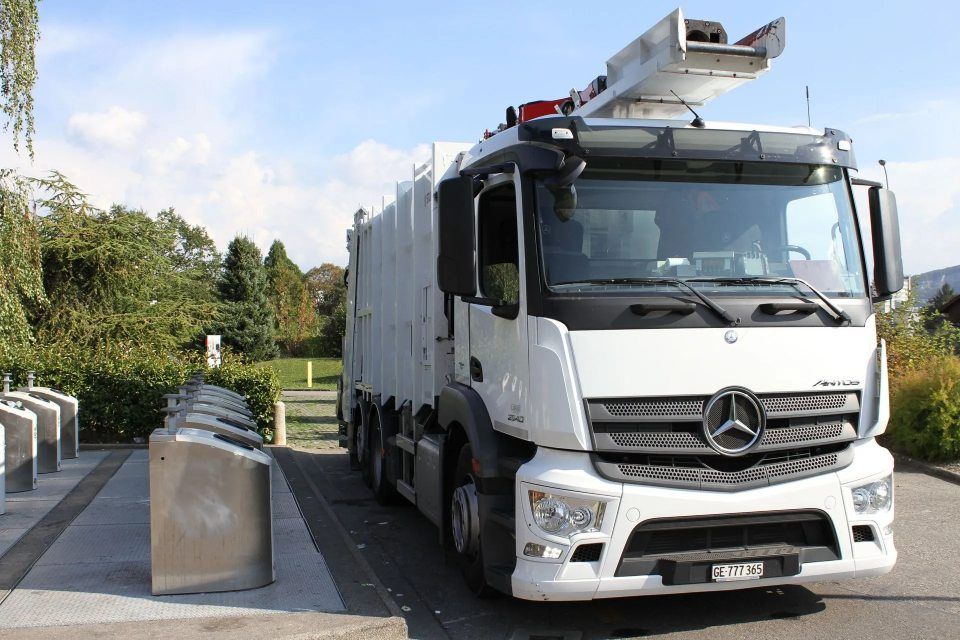 Un camion poubelle blanc est garé sur le bord de la route.