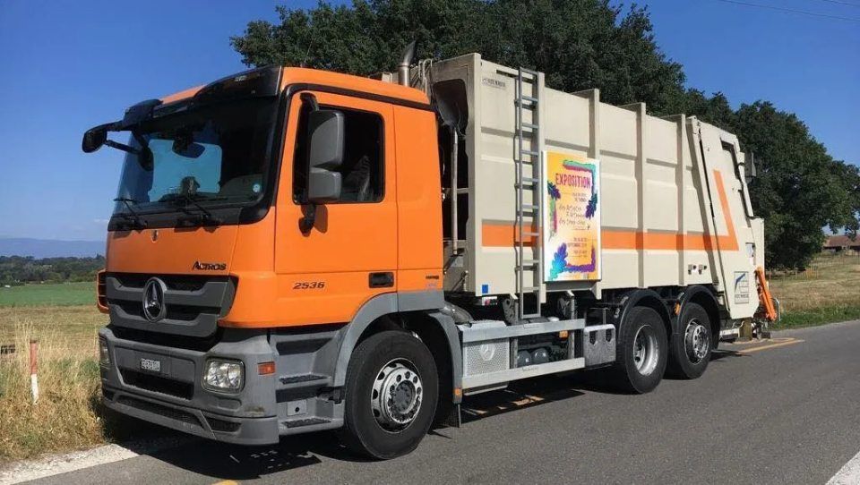 Un camion poubelle est garé sur le bord de la route.