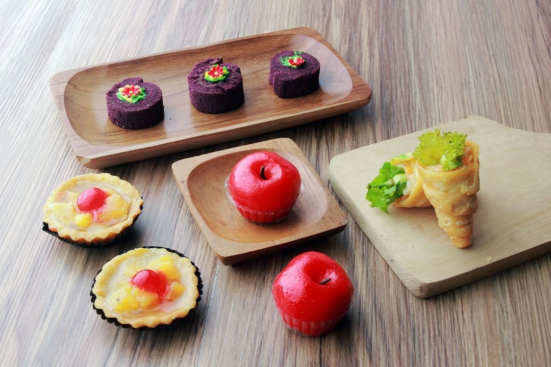 Surtido de coloridos postres pequeños en bandejas de madera sobre una mesa de madera.