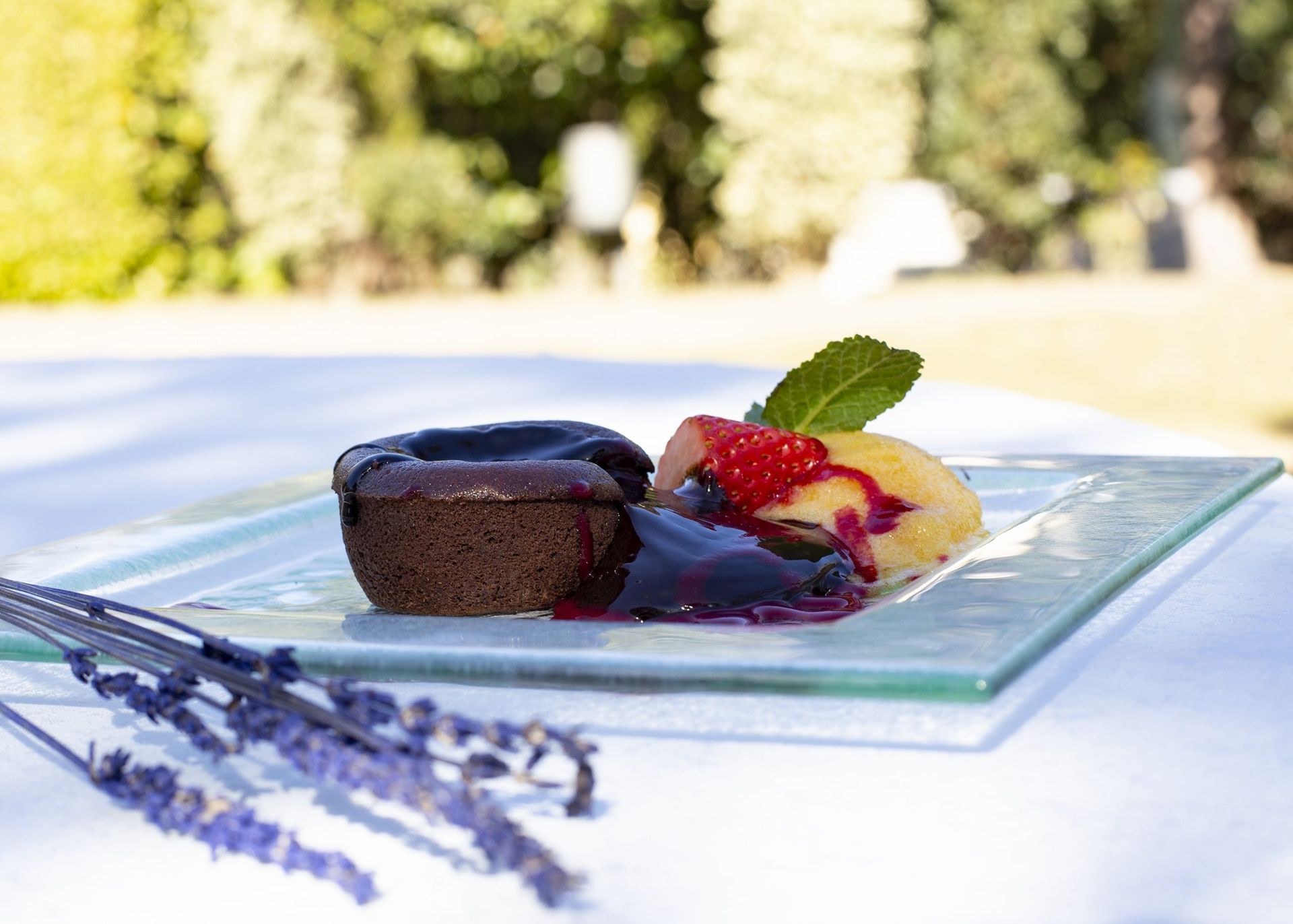 Pastel de lava de chocolate con helado, frutos rojos y lavanda en un plato de cristal. Al aire libre.
