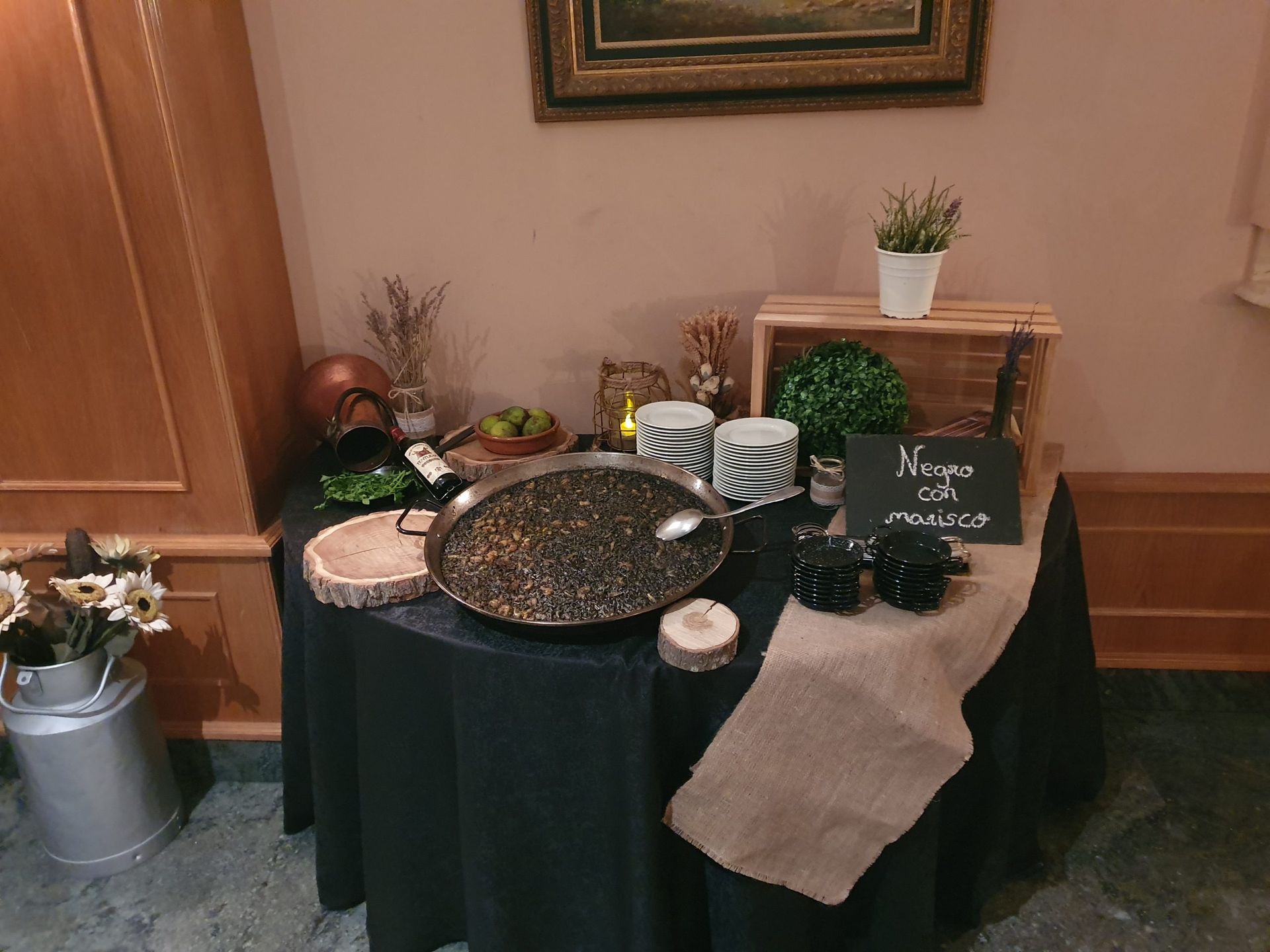 Mesa dispuesta con paellera, tapas y platos expuestos para servir.