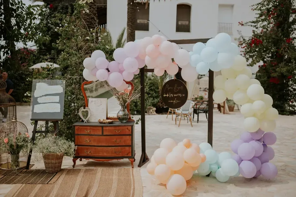 Los arcos de globos de arcoíris enmarcan una decoración rústica para la celebración de una boda.
