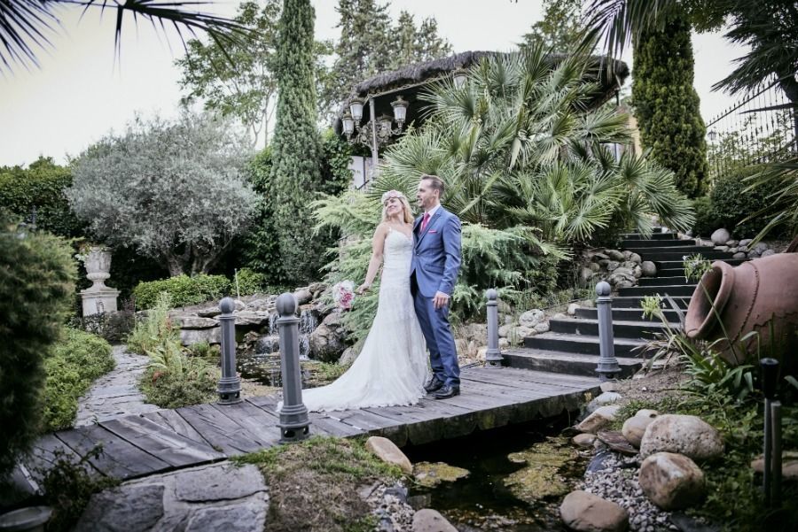 Los novios posan en un puente de madera en un exuberante jardín, una foto de boda.