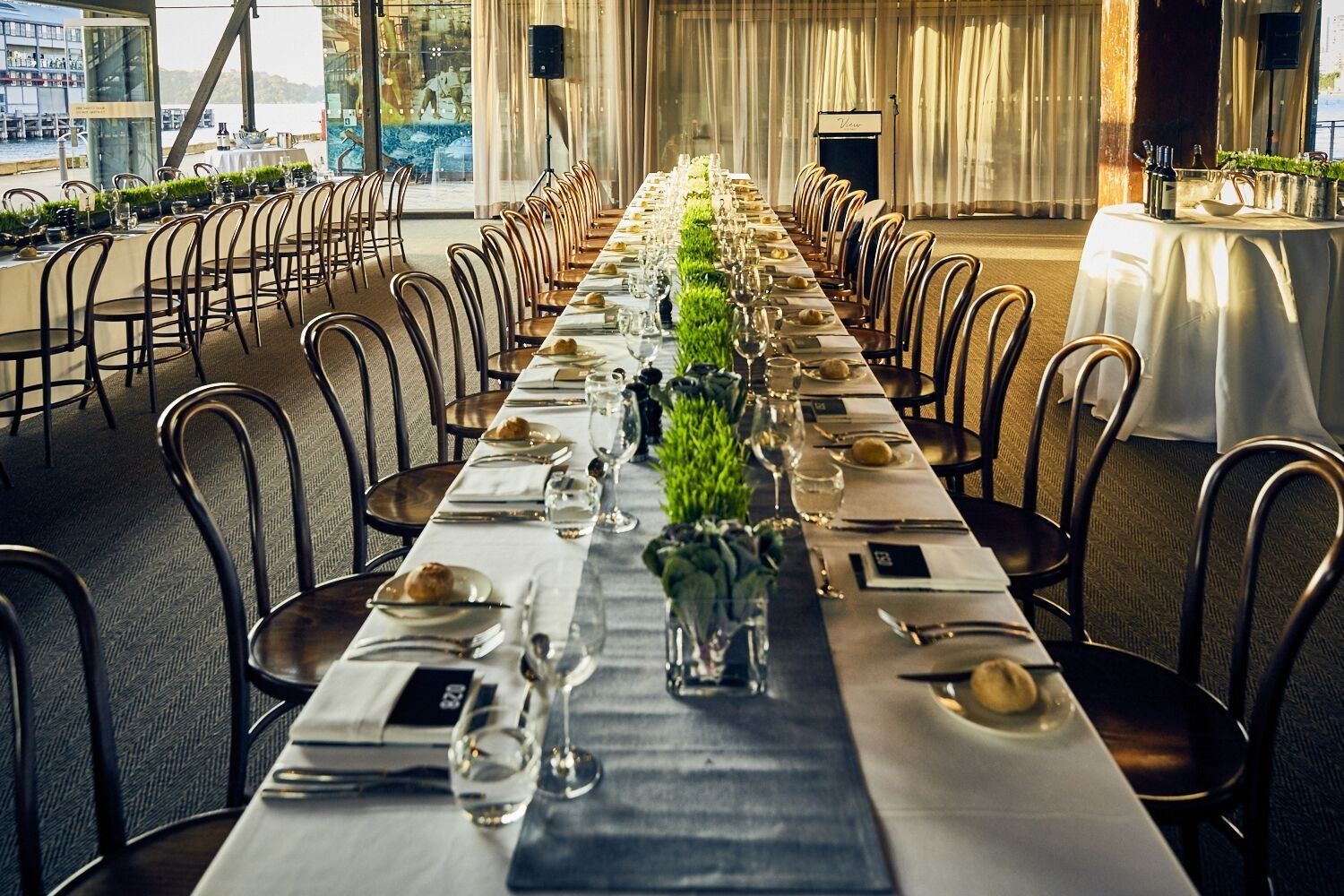 Mesa formal larga para una cena, con sillas, vajilla y centros de mesa.