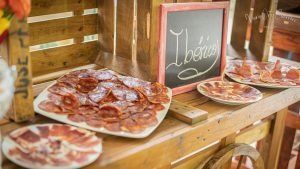 Tabla de embutidos con jamón ibérico loncheado y chorizo ​​expuestos sobre soporte de madera.