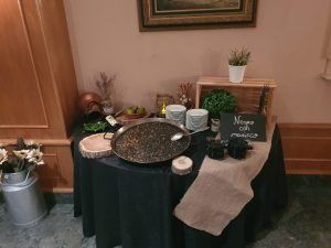 Una mesa con un mantel negro que sostiene una gran paellera llena de arroz negro, un cartel dice 