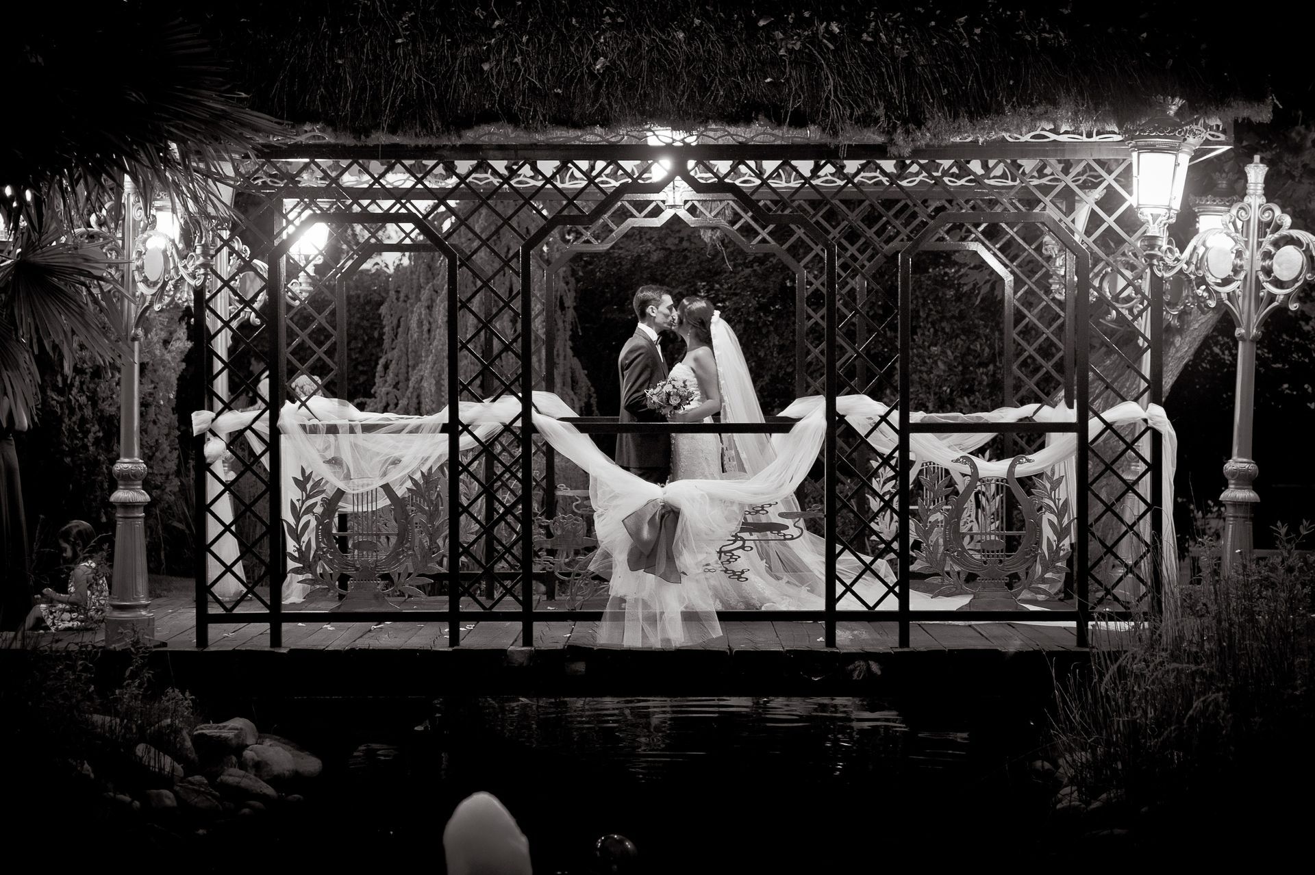 Una pareja se besa en un cenador decorado para una boda. Blanco y negro.