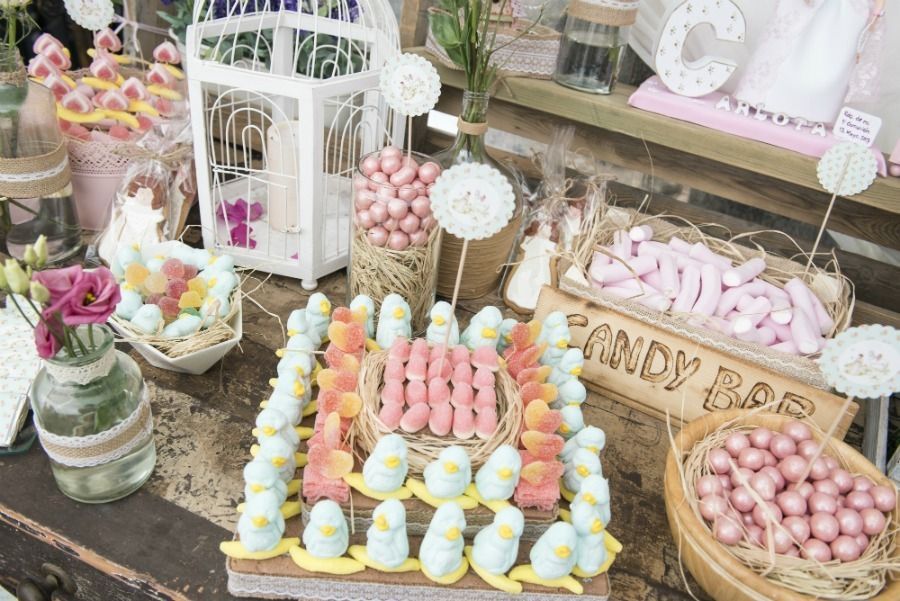 Barra de dulces con diversos dulces rosas y azules, cajas de madera y decoraciones florales.