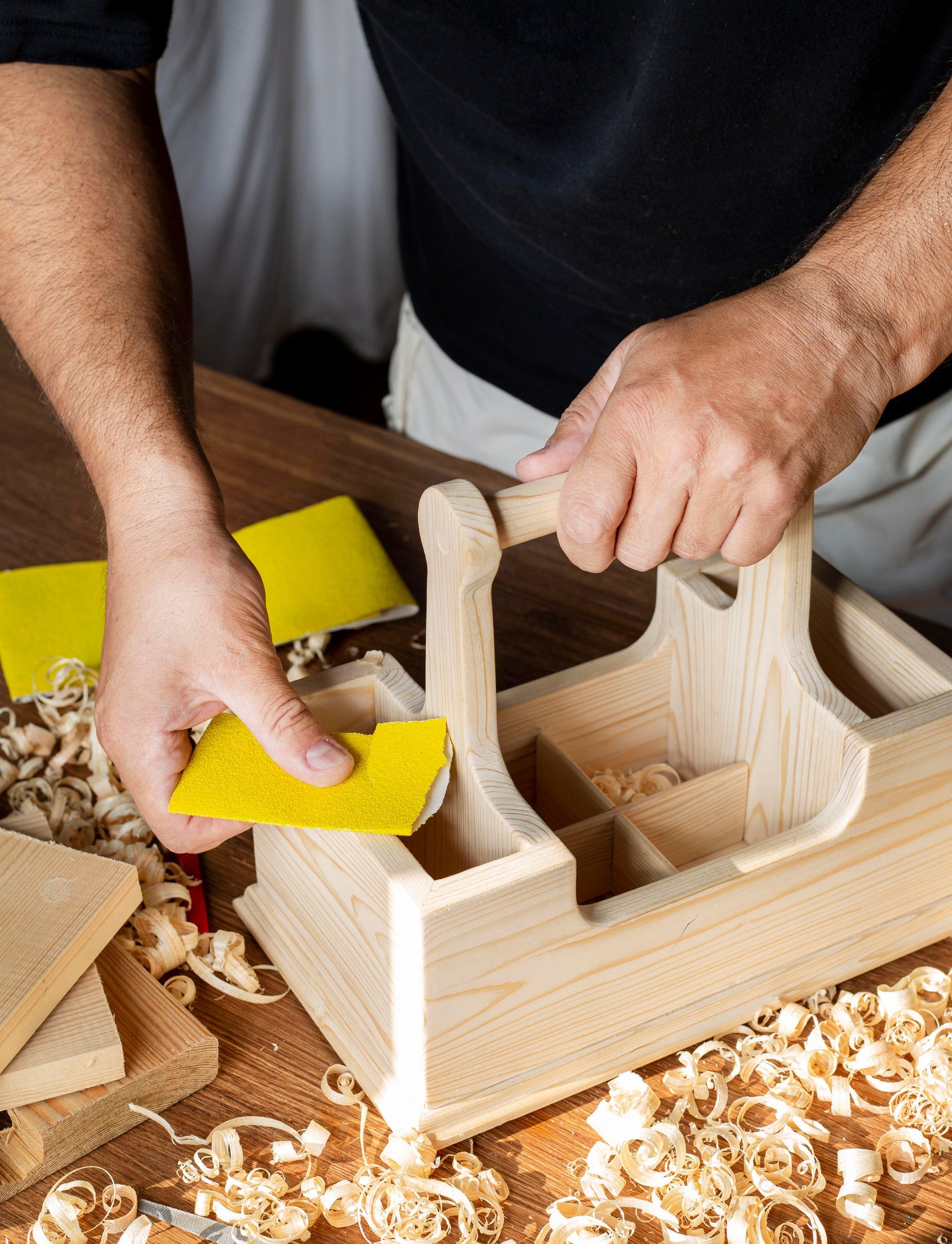 Un hombre está lijando un trozo de madera en una mesa.