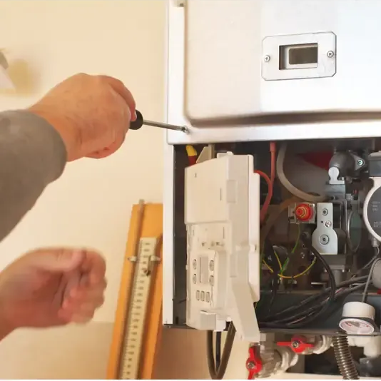 Persona que utiliza un destornillador para trabajar en el interior de un horno.