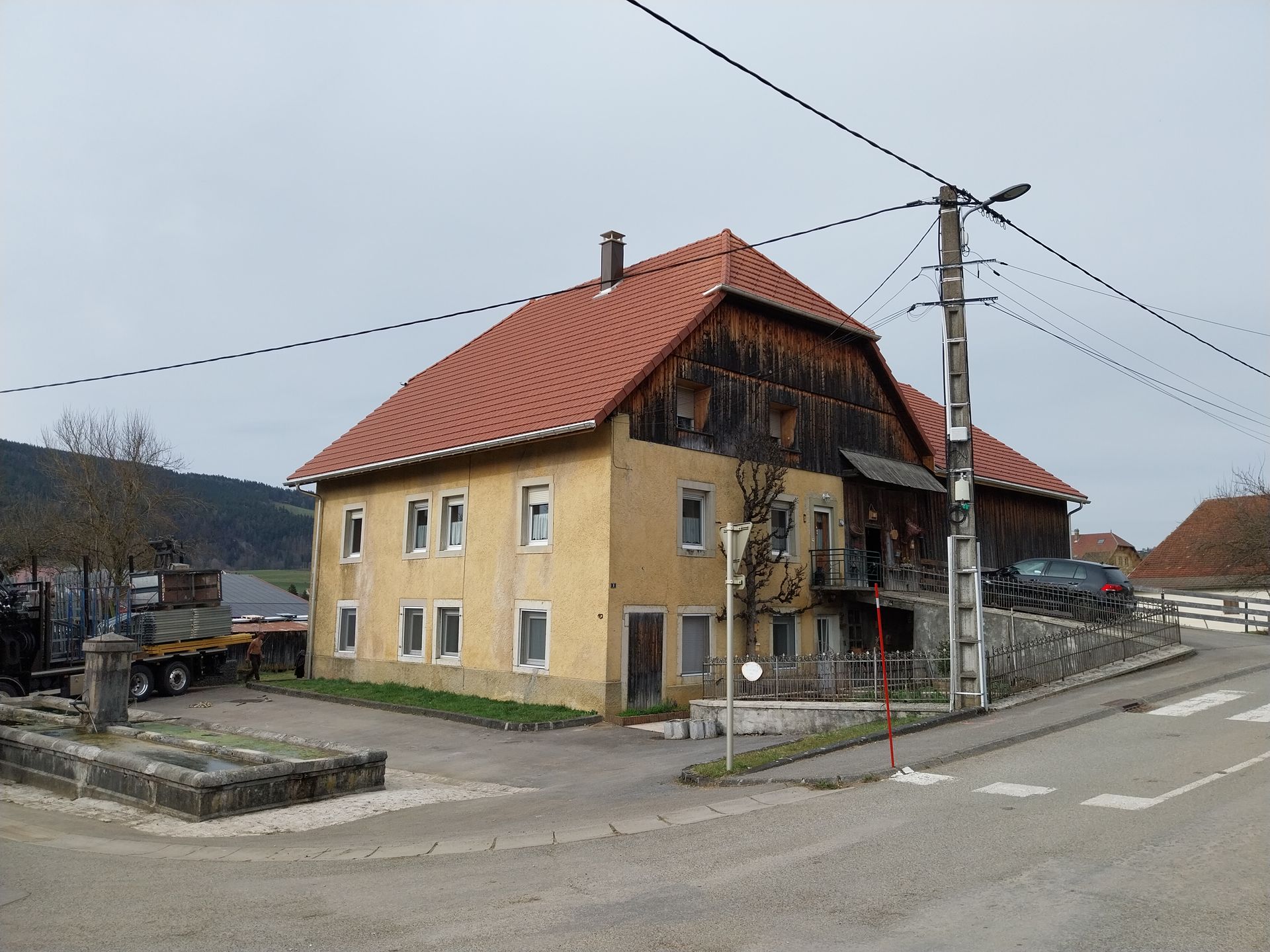 Bâtiment jaune au toit rouge et à façade en bois, situé à l'angle d'une route.