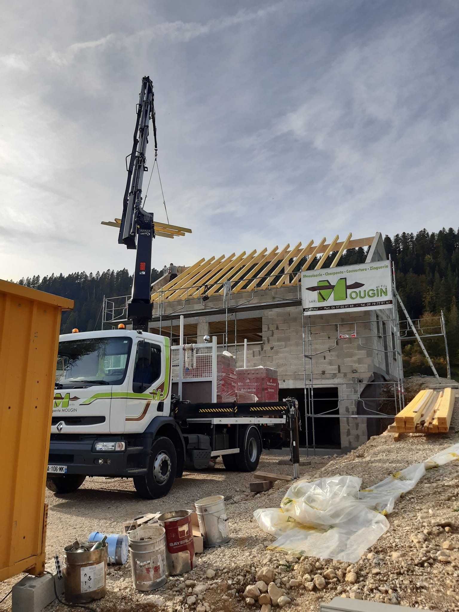 Chantier de construction : un camion-pompe à béton dépose du béton sur la structure d'une maison. Ciel couvert.