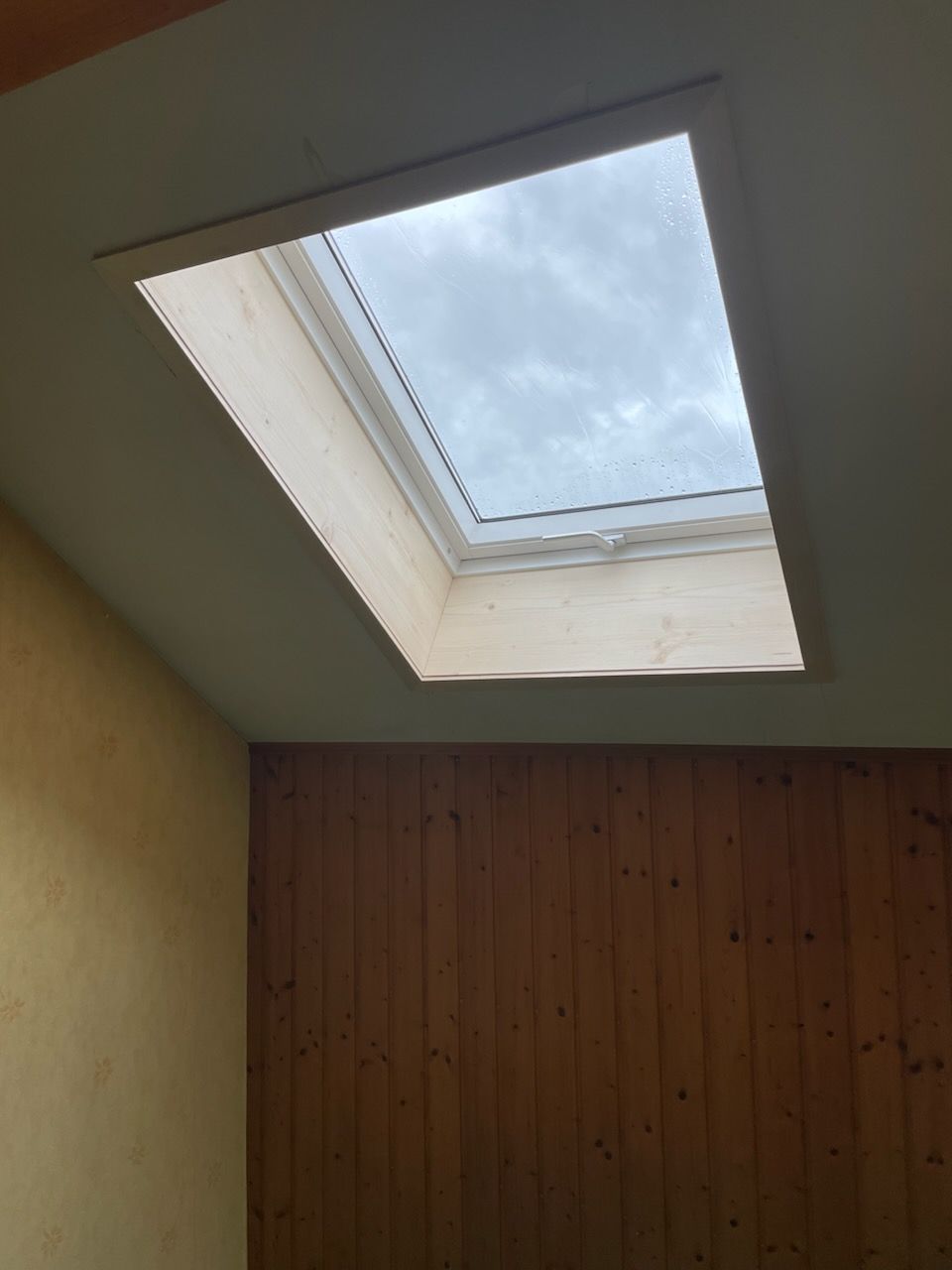 Puits de lumière dans une pièce aux boiseries apparentes.