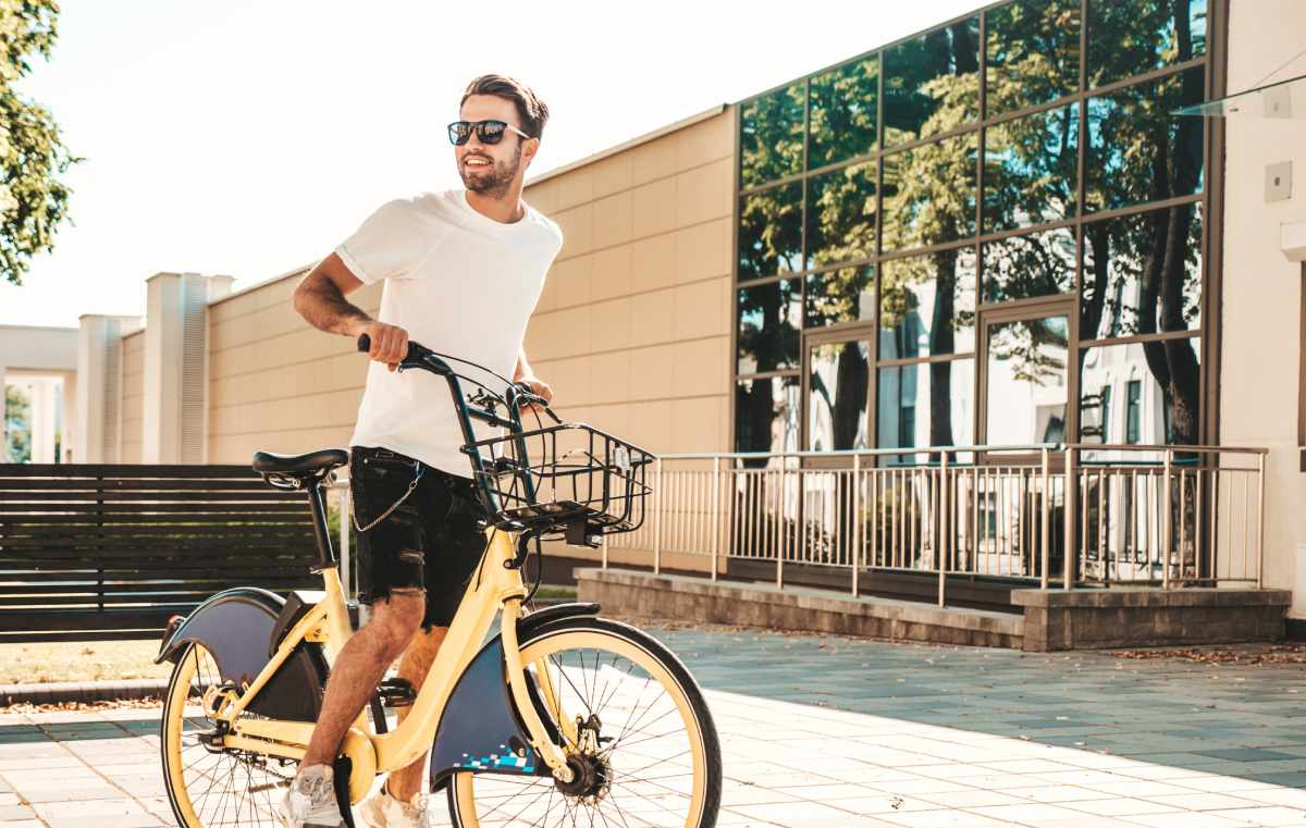 A man is riding a yellow bicycle on a sidewalk in front of a building.
