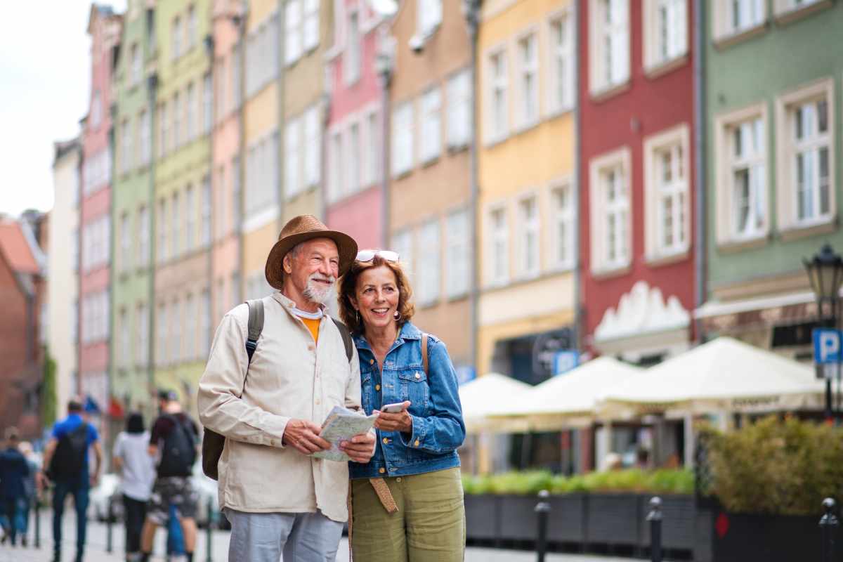 An elderly couple is standing on a city street looking at a map.
