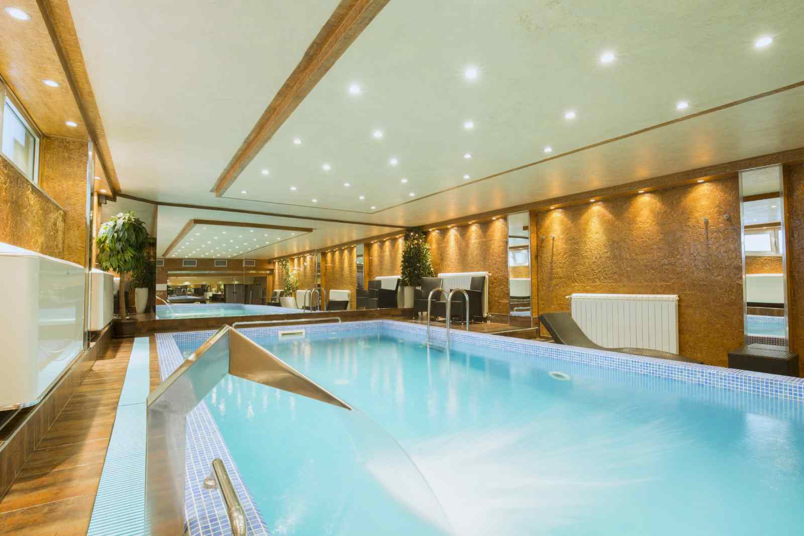 A large indoor swimming pool with a waterfall in a hotel.
