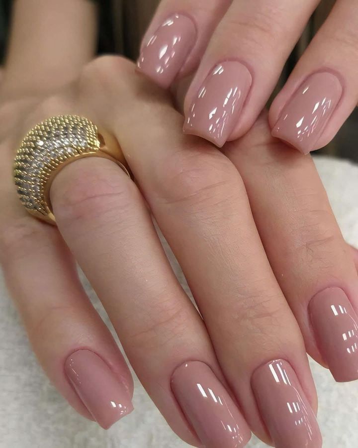Mains avec vernis à ongles turquoise, un ongle avec un motif floral, reposant sur une surface rose.