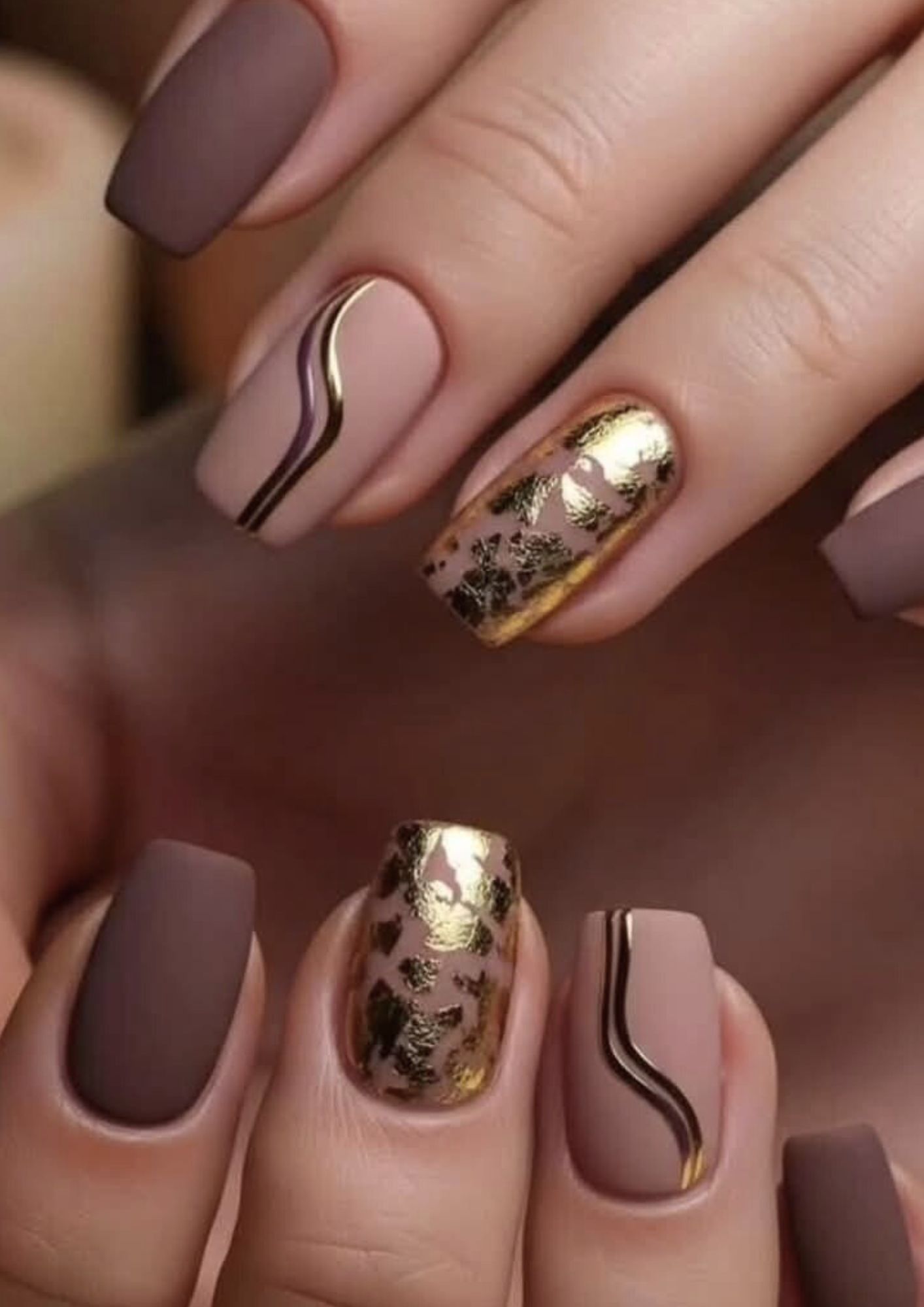 Main aux ongles courts et arrondis peints avec du vernis rose clair.