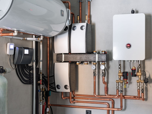 Chaufferie avec réservoir d'eau blanche, radiateur mural et tuyauterie en cuivre pour le chauffage.