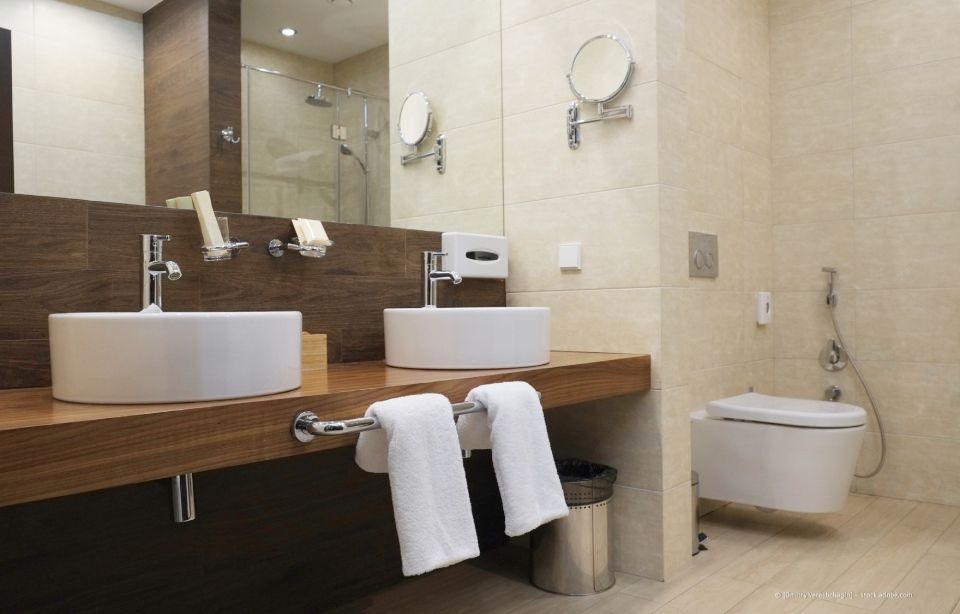 Luxuriöses Badezimmer: Marmorwände/-boden, goldene Armaturen, Whirlpool-Badewanne, Doppelwaschtisch, gerahmter Spiegel.