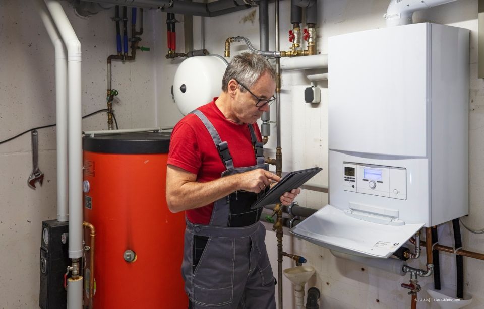 Komponenten eines Heizsystems, silberner Tank und grauer Kasten, in einem Haus.