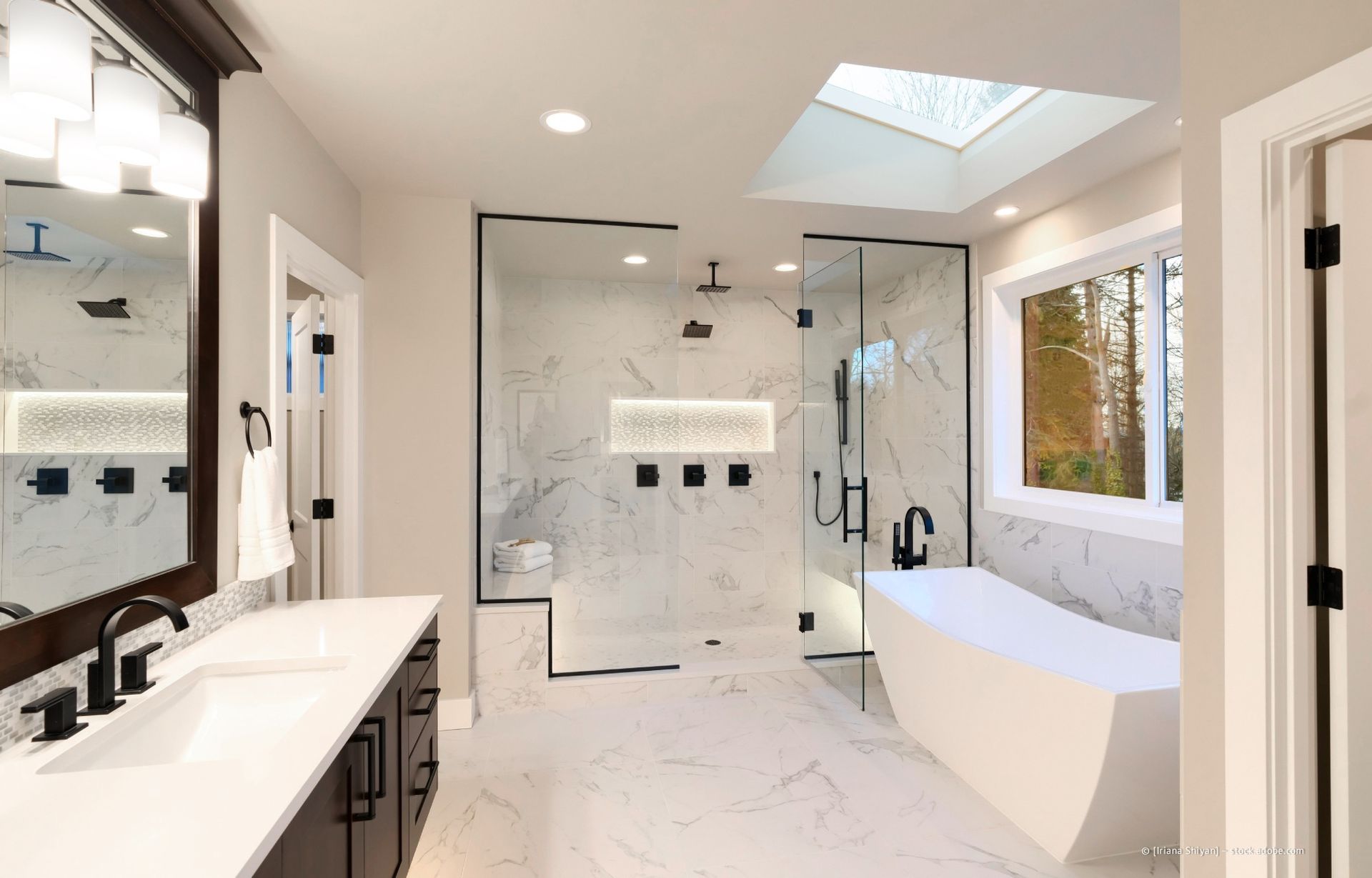 Modernes Badezimmer mit Marmorfliesen, Glasdusche, Badewanne und Oberlicht.