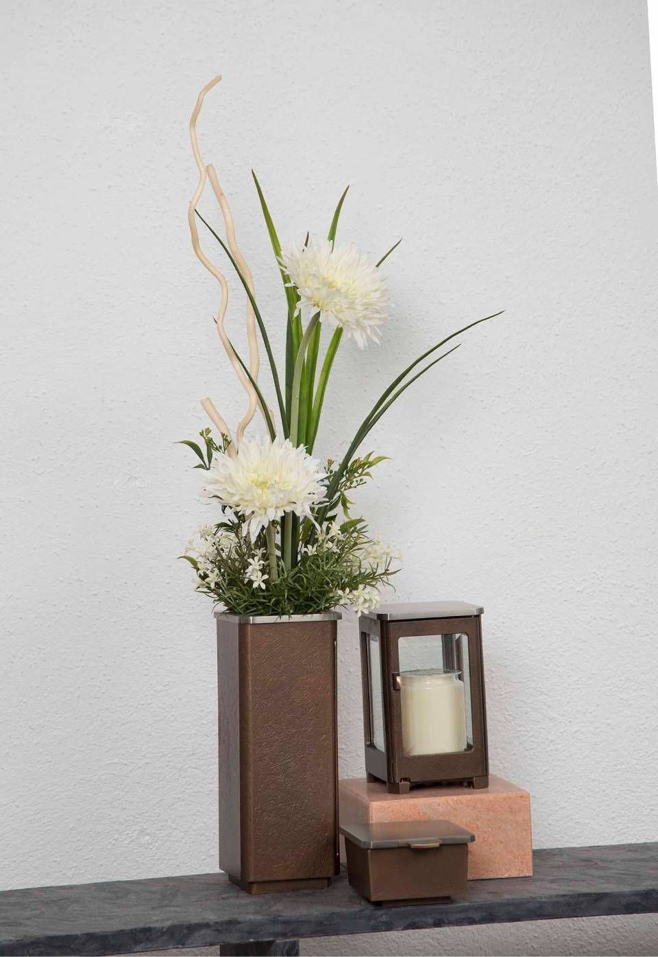 Blumenarrangement mit weissen Blumen, hohe braune Vase, Laterne und Schachtel auf einem Regal.