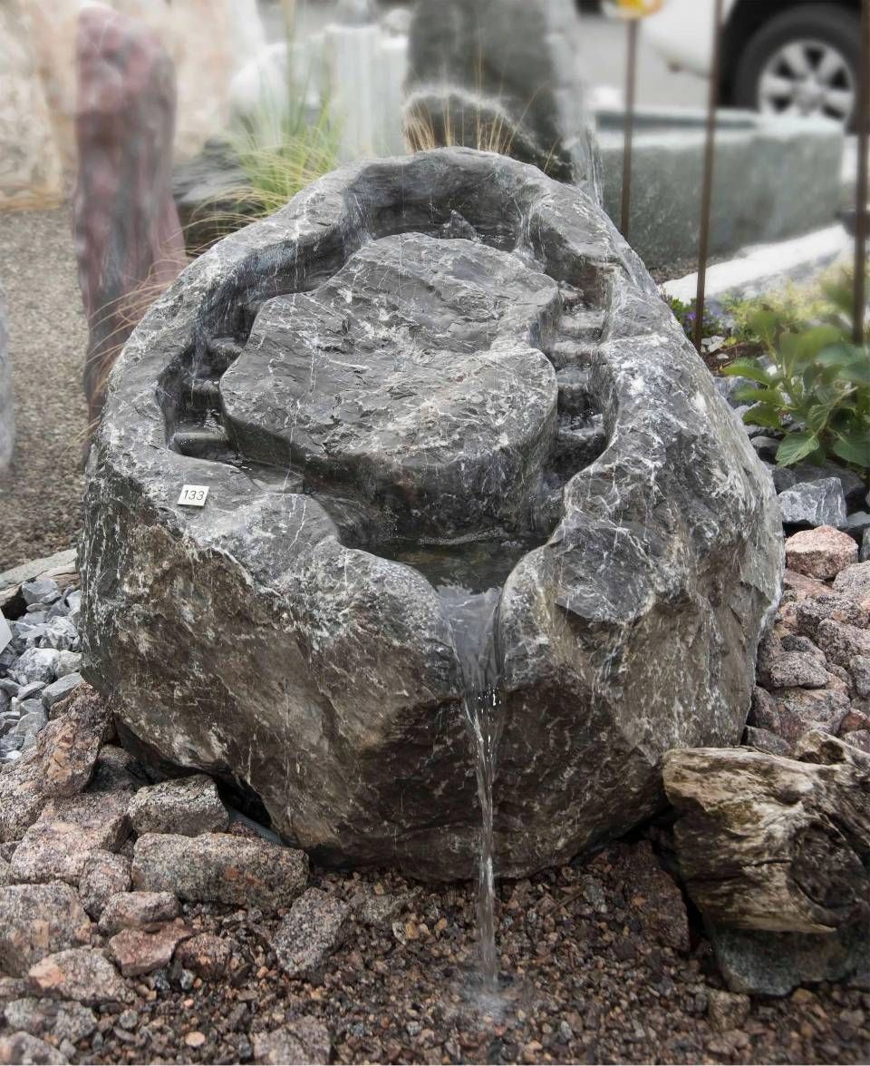 Granitfelsenbrunnen mit herabstürzendem Wasser.