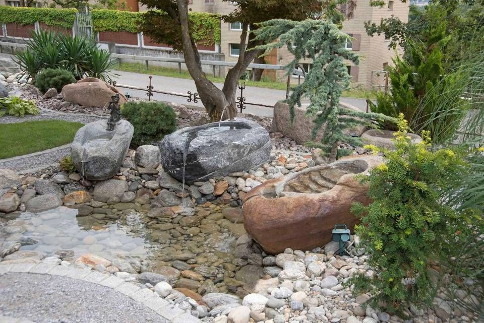 Steingarten mit Wasserspiel; grosse Steinbecken, Bachlauf, Grünflächen und kleine Bäume.