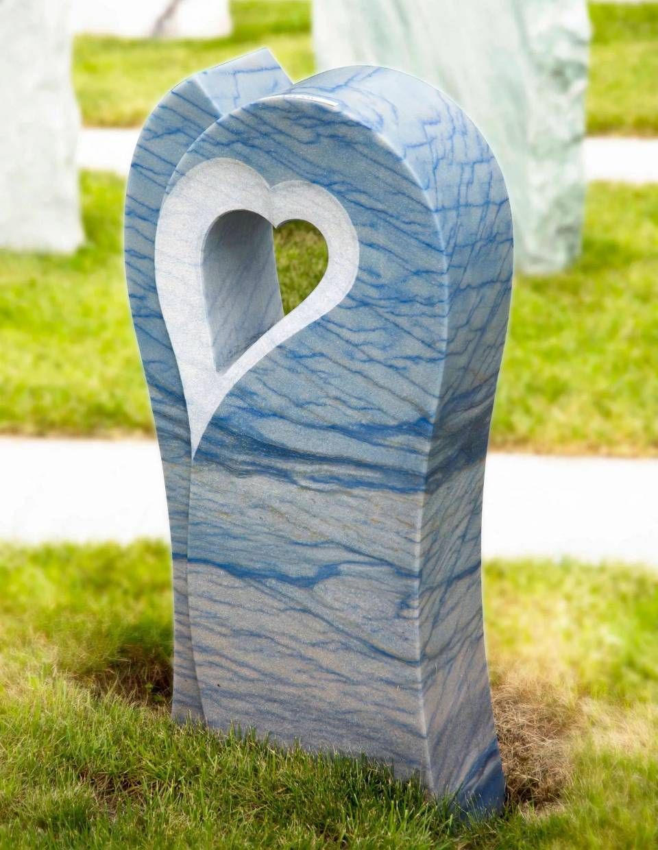 Denkmal aus blauem Marmor mit herzförmigem Ausschnitt, eingebettet in eine Rasenfläche.