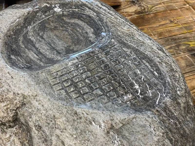 Steinschnitzerei eines Mobiltelefons, detaillierte Tastatur und Ohrhörer sind erkennbar.
